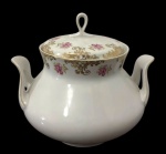 MAUÁ. Antiga sopeira em porcelana nacional branca, decorada com rosas e folhagens, intercaladas por arabescos e filetes dourados. Corpo bojudo, alças laterais vazadas e tampa com puxador em argola. Medidas: 24 x 21 x 21,5 cm.