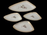 Conjunto de quatro peças em porcelana, composto por uma travessa e três pratinhos de formato triangular com cantos arredondados, decoração floral em tons de rosa e folhagens, bordas com douração pontilhada e filetes dourados. Marca no verso. Medidas: travessa, 3 x 30,5 x 17,5 cm; pratinhos, 1,5 x 18 x 10,5 cm