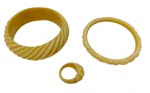 Marfim. Três peças em marfim entalhado, composto por dois braceletes rígidos, sendo um largo com caneluras oblíquas e outro estreito com rosas e folhagens em relevo, e um anel com caneluras. Anel: aro 17.