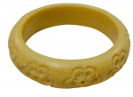 Antigo bracelete rígido em marfim entalhado, de formato circular, com face externa abaulada, decorada com flores em relevo, e interior liso.