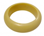 Bracelete rígido em marfim, de formato circular e perfil largo, com face externa abaulada, superfície lisa e polida.