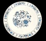 Antiga travessa circular em ágata (metal esmaltado), com fundo branco e decoração de flores, folhagens e arabescos em azul e preto. Marcas de uso na superfície. Medidas: 3 cm de altura x 40,5 cm de diâmetro.