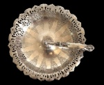 Cesta em metal espessurado a prata, com alça decorada com motivos florais em relevo, borda recortada e vazada e corpo ornamentado com reservas florais gravadas em disposição radial. Medidas: 22 x 23 x 9 cm.