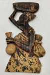Talha decorativa de parede em madeira entalhada e policromada, representando figura feminina de perfil, com recipiente sobre a cabeça e vasilha junto ao corpo. Apresenta desgastes e perdas na pintura. Medidas: 34 x 17 cm.