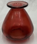Vaso em vidro translúcido na cor vermelha, com corpo piriforme, gargalo curto e borda larga evertida. Apresenta marcas de uso e riscos superficiais. Medidas: 24 x 19 cm.