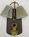 Arandela de duas luzes, com suporte em madeira recortada, haste em metal dourado e ornamento em forma de escafandro. Acompanha duas cúpulas cônicas com revestimento desfiado e perdas acentuadas. Apresenta desgaste no acabamento e marcas de uso. Medidas: 43 x 35 x 11 cm.