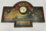 Relógio de parede com caixa em metal dourado, aplicado sobre placa de madeira recortada e moldurada, com decoração policromada de temática náutica e inscrições OCLOCK e Keep the Watch. Mostrador com algarismos arábicos e indicação de 24 horas. Apresenta desgaste na pintura, riscos, pequenas perdas na madeira e oxidação no metal. Funcionamento não testado, sem garantias. Medidas: 41 x 60 x 8 cm.