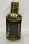 Lanterna em metal dourado, com corpo semicilíndrico, porta frontal com vidro, chaminé com orifícios de ventilação e suporte posterior para fixação. Apresenta amassados, riscos e pontos de oxidação. Medidas: 26 x 11 cm.
