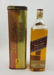 Whisky escocês Johnnie Walker Red Label, blended Scotch whisky, produzido por John Walker & Sons, Kilmarnock, Escócia. Acondicionado em garrafa original de 1 litro, com lacre e rótulos preservados, acompanhado de sua lata original litografada da marca. Exemplar destinado ao mercado internacional, reunindo garrafa e embalagem promocional de época. Conteúdo não atestado.