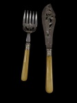 Lote contendo 2 talheres para servir, sendo 1 garfo de servir e 1 espátula para peixe, produzidos em metal espessurado a prata, com cabos em tom marfim e detalhes decorativos em relevo. Medidas: 24 cm e 32 cm.
