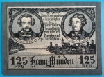 Alemanha (Hann. Münden), 1922. Cédula de emergência (Notgeld) com o valor nominal atípico de 1,25 Mark (125 Pfennig), emitida pelo conselho municipal. O anverso apresenta os retratos biográficos em medalhões do compositor Gustav Pressel e do poeta Franz von Dingelstedt, criadores da célebre canção cultural "Weserlied", posicionados sobre uma bela vista panorâmica em bico de pena da silhueta da cidade e sua ponte histórica. O reverso exibe uma poética e bucólica gravura intitulada "An der Weser" (Às Margens do Weser), retratando um músico romântico tocando alaúde sob a sombra de uma árvore, contemplando um barco navegando pelo rio em meio às montanhas. O grande destaque artístico é a inclusão da pauta com as notas musicais da melodia oficial no topo. Uma peça soberba e indispensável de temática musical e lírica da República de Weimar, catalogada sob a referência Mehl #530.1c