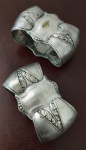 Dois antigo porta guardanapos  em formato de laço com detalhes em relevo de folhas .Espessurada a prata .Medida : 7x3x3 cm.