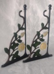 Dois suportes para prateleiras em ferro fundido, com decoração floral policromada. Medindo 29 x 18 cm.
