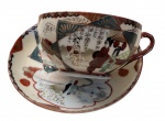 SATSUMA - Xícara de chá com pires em porcelana japonesa, dito casca de ovo, decoração oriental policromada com figuras em trajes típicos, reservas e detalhes em douração, no estilo Kutani/Satsuma. Em bom estado de conservação.