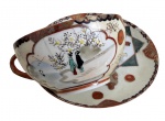 Antiga xícara de chá em delicada porcelana japonesa dita casca de ovo, com decoração policromada com figuras orientais, paisagem e flores, com detalhes em dourado. Possui fio de cabelo. Acompanha pires. Circa 1900.
