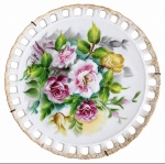 Prato de parede em porcelana japonesa SHOFU CHINA, com decoração floral policromada pintada à mão, composição de rosas e folhagens, borda vazada e detalhes dourados. Assinado. Resquícios de vibrante ouro. Marcas do tempo. Circa 1900. Sinal de restauro. Mede 21 cm de diâmetro.