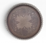 Bandeja circular em metal, de três pés, com rica decoração ornamental gravada e borda vazada, apresentando inscrição dedicatória ao centro. Marcas do tempo. Mede 37 cm de diâmetro.