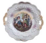 EUROPA SÉC. XIX - Medalhão em porcelana europeia, decorada com cena campestre central representando duas camponesas, pintura policromada, detalhes em ouro e alças laterais vazadas. Meados século XIX. Desgaste do tempo. Mede 27,5 cm de diâmetro.