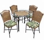 CONJUNTO DE MESA E QUATRO CADEIRAS para varanda, de inspiração tropical, composto por mesa circular com tampo de vidro translúcido, estrutura em metal escuro e detalhes em fibra trançada, acompanhada de quatro cadeiras com encosto e assento em fibra natural trançada, estrutura metálica e almofadas estofadas com tecido estampado em motivos de folhagens em tons de verde. Conjunto de caráter decorativo e funcional, de estética leve e apropriado para ambientes internos ou varandas. Medidas: