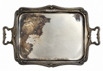 Bandeja retangular em metal prateado, de formato clássico, com borda trabalhada e alças laterais ornamentadas. Apresenta sinais de uso e marcas do tempo, preservando características de sua época. Necessita novo banho de prata. Mede 65 x 42 cm.