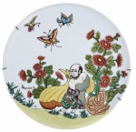 Medalhão decorativo em porcelana, decoração policromada de inspiração oriental, com figura humana, flores e borboletas, acabamento delicado e assinatura aparente  Maria-V.. Verso com revestimento em veludo vermelho e aramado para fixação. Mede 24 cm de diâmetro.