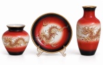 CONJUNTO DE PORCELANA com  decoração oriental com dragões em dourado e esmaltação em vermelho e preto, composto por dois vasos e prato. Peças com detalhes dourados. Marca na base. Maior mede 14 cm de altura.