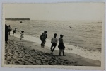 Foto Época (c. 1950) Banhistas na Praia com Carimbo "Foto-Carval Famalicão"  Borda Canoa Belíssimo registro em preto e branco que captura a atmosfera de lazer costeiro da época. A imagem mostra diversas pessoas (adultos e crianças) caminhando na beira do mar e na faixa de areia. Ao fundo, no canto superior esquerdo, destaca-se uma estrutura de pedra que se assemelha a um molhe, quebra-mar ou porto. Detalhes do Verso: O grande diferencial que localiza a origem e a autoria do item é o elegante carimbo em relevo timbrado no canto inferior esquerdo: "Foto-Carval FAMALICÃO" (Estúdio fotográfico histórico da cidade de Vila Nova de Famalicão, Portugal).