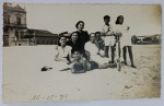 Foto Época (10-10-1939) Família na Praia com Bicicleta Antiga e Arquitetura Histórica ao Fundo  Borda Canoa Raro e belíssimo registro social em preto e branco que captura uma grande família (mulheres, jovens e crianças) reunida na areia da praia. A imagem é rica em elementos de época de altíssimo apelo colecionável