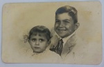 Foto Estúdio Kauffmann Santos (1948) Retrato de Irmãos Roberto e Regina com Carimbo e ChancelaClássico e expressivo retrato de estúdio em preto e branco (tom sépia) mostrando duas crianças: um menino sorridente vestindo paletó e gravata e uma menina com laços no cabelo. No canto inferior direito da imagem, há a chancela em relevo seco original do estúdio ("Kauffmann Foto Santos").