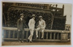 Foto Histórica Época (c. 1910/1920) Senhores de Terno, Chapéu de Palheta e Bengala junto a BalustradaRaro e elegante registro masculino em tom sépia, capturando três cavalheiros de alta classe social posando em uma área externa. A cena destaca-se pela riqueza de elementos da moda e comportamento da elite na virada da Belle Époque para os anos 20: