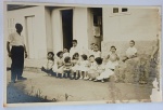 Foto Época (c. 1950) Aniversário ou Festa Infantil com Balões e Grande Grupo de CriançasExpressivo e nostálgico registro social focado na infância de meados do século XX. A cena captura um numeroso grupo composto por cerca de doze crianças vestindo trajes finos de festa (meninas com vestidos brancos rodados e meninos de camisa social clara).