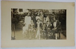 Foto Época (c. 1920/1930) Retrato de Grande Grupo Familiar com Cadeiras Thonet em JardimAlém do rico vestuário que ilustra a transição da moda dos anos 20 para os anos 30 (como saias plissadas, ternos infantis com shorts de alfaiataria e os cortes de cabelo femininos curtos), destaca-se na cena o uso de cadeiras antigas de madeira escura com encosto arqueado (estilo clássico Thonet / austríaco) dispostas no quintal para a pose do grupo.