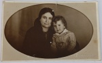 Foto Época (c. 1910/1920) Retrato Oval de Mãe e Filho  Estúdio Phot. Bernardo (Rua São Caetano, SP)Magnífico e afetuoso retrato de estúdio emoldurado por um elegante formato oval integrado ao papel fotográfico. A imagem captura uma senhora vestida com trajes escuros discretos de época abraçada a um menino de cabelos cacheados, que veste uma charmosa camisa listrada com cinto embutido