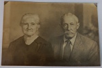 Foto Época (1950) Retrato de Casal de Senhores com Carimbo de Campinas  Papel EurydesSolene e expressivo retrato de estúdio focado no busto (plano médio) de um casal de senhores de idade avançada. A senhora traja uma blusa escura de gola em "V", típica dos anos 1940/1950, e o cavalheiro exibe um imponente bigode clássico, vestindo paletó claro texturizado, camisa social branca e gravata listrada.