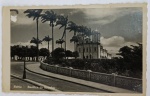 Foto Antiga Época (c. 1940/1950) Basílica do Bonfim, Salvador - Bahia  Borda Canoa Belíssimo e clássico registro panorâmico da colina sagrada em Salvador - BA. A composição destaca a imponente fachada colonial da Igreja de Nosso Senhor do Bonfim (Basílica do Bonfim), ladeada por altos coqueiros inclinados pelo vento, postes de iluminação pública antigos, muretas decorativas vazadas de concreto e a praça frontal.