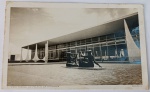 Foto Postal Histórica (c. 1960) Vista do Palácio da Alvorada e Escultura "As Iaras"  Brasília Espetacular e icônico registro em preto e branco que documenta a modernidade da nova capital federal. A imagem destaca a fachada geométrica e as colunas características do Palácio da Alvorada, projetado por Oscar Niemeyer. Em primeiro plano, no espelho d'água, repousa a famosa escultura em bronze "As Iaras" (também conhecida como "As Banhistas"), de autoria do renomado artista Alfredo Ceschiatti.