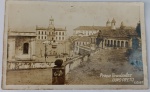 Foto Postal Ouro Preto (c. 1930) com Poema Manuscrito de Alphonsus de Guimaraens  Assinado Magnífico registro em tom sépia da Praça Tiradentes em Ouro Preto - MG, destacando o Museu da Inconfidência, carros de tração animal e casarios coloniais (Código C.O. 57). Riquíssimos Detalhes do Verso (Transcrição Íntegra):O verso traz a cópia manuscrita de uma das estrofes do famoso poema mariano do mestre do Simbolismo brasileiro:Alphonsus de Guimaraens, cuja história de vida está profundamente ligada às cidades históricas mineiras  possuem um forte apelo no nicho de autógrafos, manuscritos raros e bibliofilia. A assinatura de "Luiz Alphonsus" (seu descendente direto) chancela a procedência cultural e eleva significativamente o valor estimado do lote.