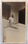Foto Época (c. 1950) Jovem Moça com Calça Estampada no Peitoril da Varanda  Charmoso, descontraído e intimista registro residencial de época. A cena captura uma jovem mulher sorridente assentada de forma espontânea sobre a mureta ou peitoril de concreto de uma varanda ou escadaria externa.