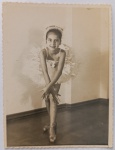 Fotografia Vintage de Época  Pequena Bailarina com Dedicatória Manuscrita (1957)Encantadora fotografia original de época (formato cartão com bordas recortadas em estilo "guilhotina" ou ziguezague, muito popular em meados do século XX). A imagem retrata uma menina vestida com traje completo de balé clássico, incluindo tutu volumoso, sapatilhas de ponta e um arranjo delicado na cabeça, posando com um sorriso expressivo em um estúdio ou sala de ensaio.