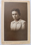 Retrato Fotográfico Vintage de Estúdio Feminino  Foto Morganti (Gualeguaychú) (c. 1930-1940)Belo e expressivo retrato fotográfico original de época, em meio-corpo, de uma jovem senhora. A imagem destaca-se pela excelente iluminação clássica de estúdio da primeira metade do século XX. A retratada posa de perfil com o rosto voltado para a frente, vestindo uma blusa ou paletó texturizado de lapela estruturada, com um broche ou detalhe decorativo no fechamento do colarinho. O cabelo está elegantemente preso e repartido ao meio, seguindo a estética sóbria da moda feminina da época.