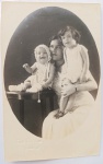Retrato Histórico (1931)  Maternidade e Infância no "Foto Silva" (Maceió - AL) com DedicatóriaBelo e raro retrato de estúdio em formato postal vertical, com máscara de revelação oval. A frente apresenta a jovem mãe (Tia Baby) com suas duas filhas pequenas (Luiza e Solange), ostentando a chancela em relevo seco do prestigiado "Foto Silva - Maceió".