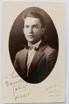  Retrato Masculino / Moda dos Anos 20 / Identificação Familiar / Eixo Alagoas. Retrato de estúdio em plano médio de busto do jovem Gabriel, posando de três quartos. Ele exibe trajes de alta alfaiataria da década de 1920, com paletó risca-de-giz e gravata borboleta de época. Inscrições na Frente: Importante dedicatória manuscrita à tinta preta na margem inferior branca: "Ao Luiz e Maria, o Gabriel / 24/10/27", direcionada aos mesmos tios Luiz e Mariinha mencionados em outros lotes do arquivo Develly.