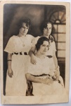  Retrato Feminino / Redes de Correspondência de Época / Moda dos Anos 20 / Documento Identificado. Retrato formal em plano médio de três jovens senhoras (Antonieta, Christina e Helena), exibindo ricos trajes civis, adornos e joias da alta sociedade de 1922. Inscrições no Verso: Rica e completa dedicatória à tinta, contendo a datação exata, a assinatura das três remetentes e a identificação do nome completo e endereço de destino da destinatária principal do arquivo, Dona Maria Augusta M. Viegas. Caligrafia clássica em estado de preservação de museu.