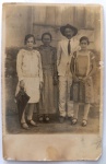   Retrato de Família / Vida Rural / Iconografia Regional / Genealogia Familiar Anterior. Retrato formal em plano inteiro de um casal com suas duas filhas em ambiente externo regional, destacando o pai com chapéu de abas largas e a jovem com sombrinha de época. Inscrições na Frente: Presença de escrita manuscrita antiga a lápis esmaecida na margem inferior direita da foto ("Affectionadas...").