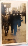  Fotografia Antiga / Fotografia de Rua Vintage (Street Snapshot / Lambe-Lambe). Época Estimada: Circa 19501958. Tema: Vida Urbana / Cotidiano / Moda Masculina e Feminina dos Anos 50 / Família Oliveira Develly. Registro instantâneo de calçada mostrando o senhor Wessel (Ary de Oliveira Develly) de terno escuro ao centro, acompanhado por um homem de terno claro à esquerda e uma senhora elegante ao fundo, caminhando em um centro metropolitano com placa indicativa "METRO".