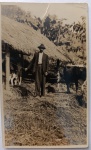  Fotografia Antiga / Cartão-Postal Fotográfico Vernacular Rústico (Real Photo Postcard - RPPC). Época Estimada: Circa 19151925 (Início do século XX). Procedência: Provável Interior de Alagoas (Eixo Engenho Valparaizo). Tema: Vida Rural / Agropecuária Antiga / Cotidiano e Trabalho / Iconografia Regional / Genealogia Familiar Anterior. Retrato vernacular em plano inteiro de um lavrador ou fazendeiro de terno e chapéu fedora gerenciando o gado bovino junto a um abrigo com teto de palha e bananal ao fundo.