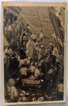   Fotografia Antiga / Cartão-Postal Fotográfico de Bordo (Real Photo Postcard - RPPC). Data Exata: 1946. Procedência: Registro de bordo em alto-mar (Navio Transatlântico). Conexão direta e fechamento da sequência em papel italiano Ferrania. Tema: Vida Marítima / Cruzeiros de Época / Batismo de Netuno / Cruzamento do Equador / Perspectiva Aérea / Curiosidades Históricas. Registro fotográfico vernacular espontâneo em plano picado mostrando a aglomeração de passageiros e tripulantes assistindo ao batismo de Netuno no convés principal do navio.