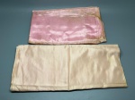 CAMA - MESA - BANHO - Conjunto de lençol e fronha em cetim rosa para cama de solteiro, com acabamento acetinado de toque suave e brilhante. Uma das peças apresenta desbotamento acentuado da cor, além de marcas do tempo e de uso, com manchas amareladas aparentes decorrentes do armazenamento.