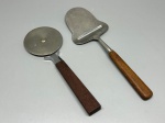 DIVERSOS - Conjunto com 2 utensílios para cozinha e mesa posta com lâmina em aço inox e cabos em madeira, composto por uma cortadora de pizza circular e uma faca/fatiadora de queijos com lâmina vazada. Apresentam leves desgastes, oxidação e marcas do tempo.