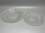 DEMI CRISTAL - Dupla de peças decorativas em vidro prensado incolor translúcido, compostas por uma travessa funda com textura granulada e motivos em espiral na aba, medindo 4 cm de altura por 23 cm de diâmetro, e um prato raso decorativo com rico relevo geométrico e floral estilo lapidado, apresentando medalhão central em estrela e borda ondulada, com 20 cm de diâmetro.